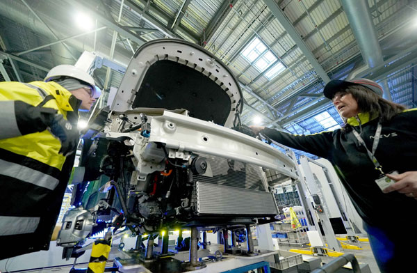 Technicians adjust manufacturing equipment at a new energy vehicle production line in Tianjin