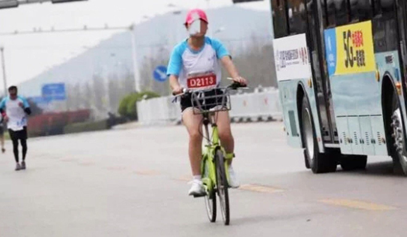 The runner rides her bicycle during the marathon despite repeated warnings to dismount