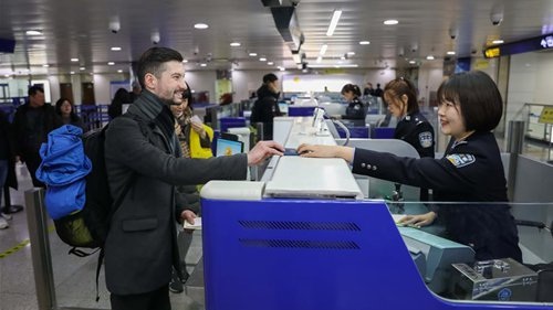Policewoman Wang Qian R helps a foreigner get cleared at immigration inspection checkpoint of the airport in Qingdao
