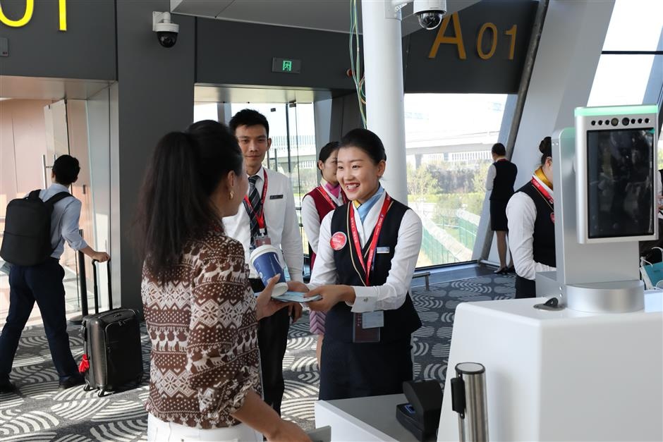 Crew members welcome the passengers at the first commercial flight at the Daxing airport