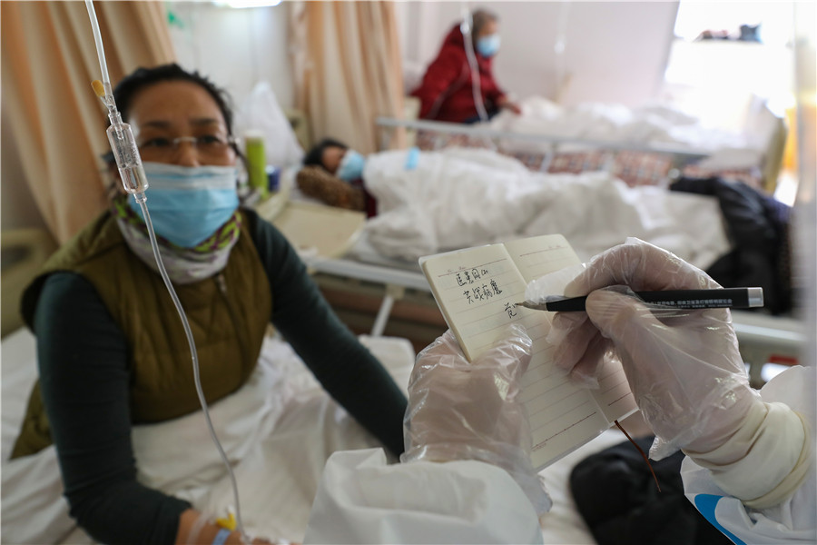 20200303 MEDICAL WORKERS Fan Zhongjie writes words of encouragement in a notebook for a patient