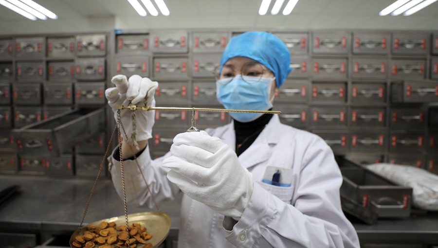 A pharmacist weighs Chinese herbal medicines for patients infected with the novel coronavirus at Anhui Provincial Hospital of Traditional Chinese Medicine in Hefei