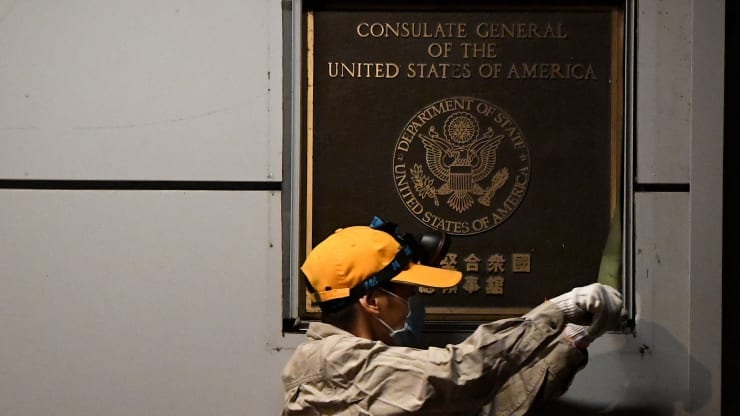 A worker attempts to remove the wall insignia of the U.S. consulate in Chengdu