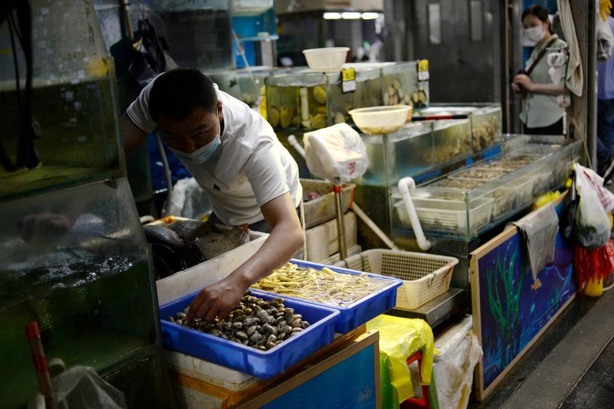 A vendor wearing a face mask prepares seafood at their stall inside the Yuegezhuang wholesale market