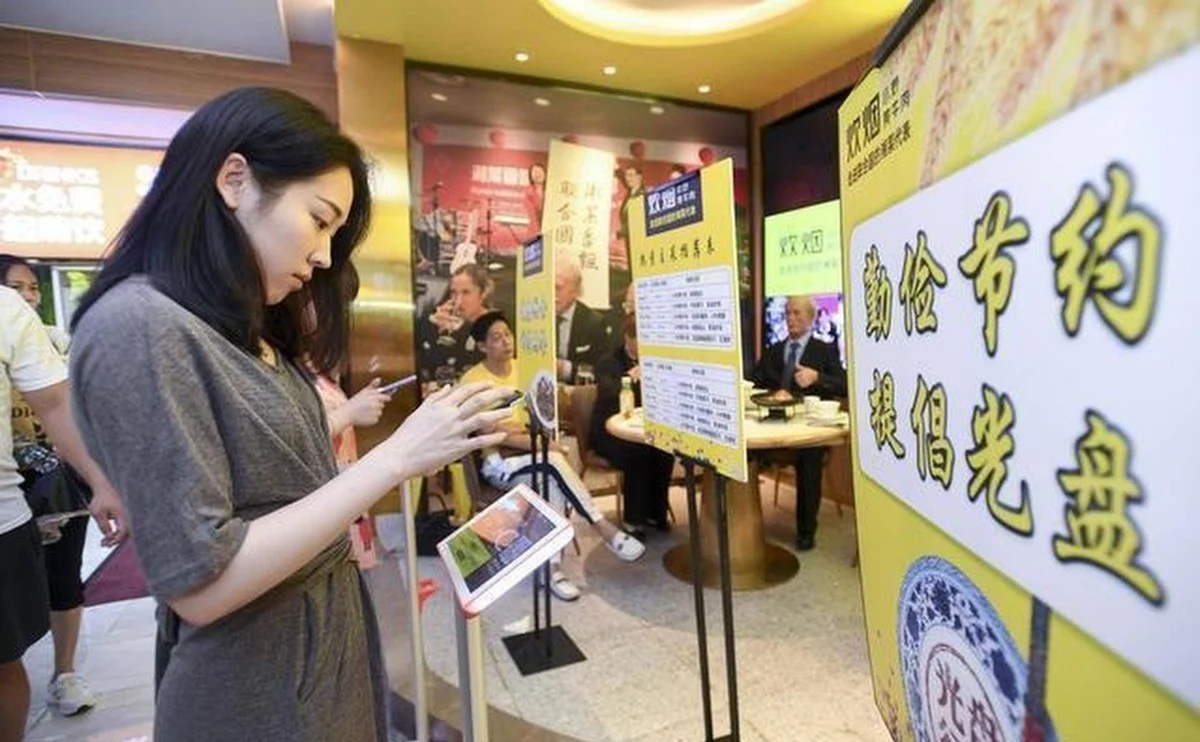 A woman checks her weight at the entrance to the Chuiyan Fried Beef restaurant in Changsha