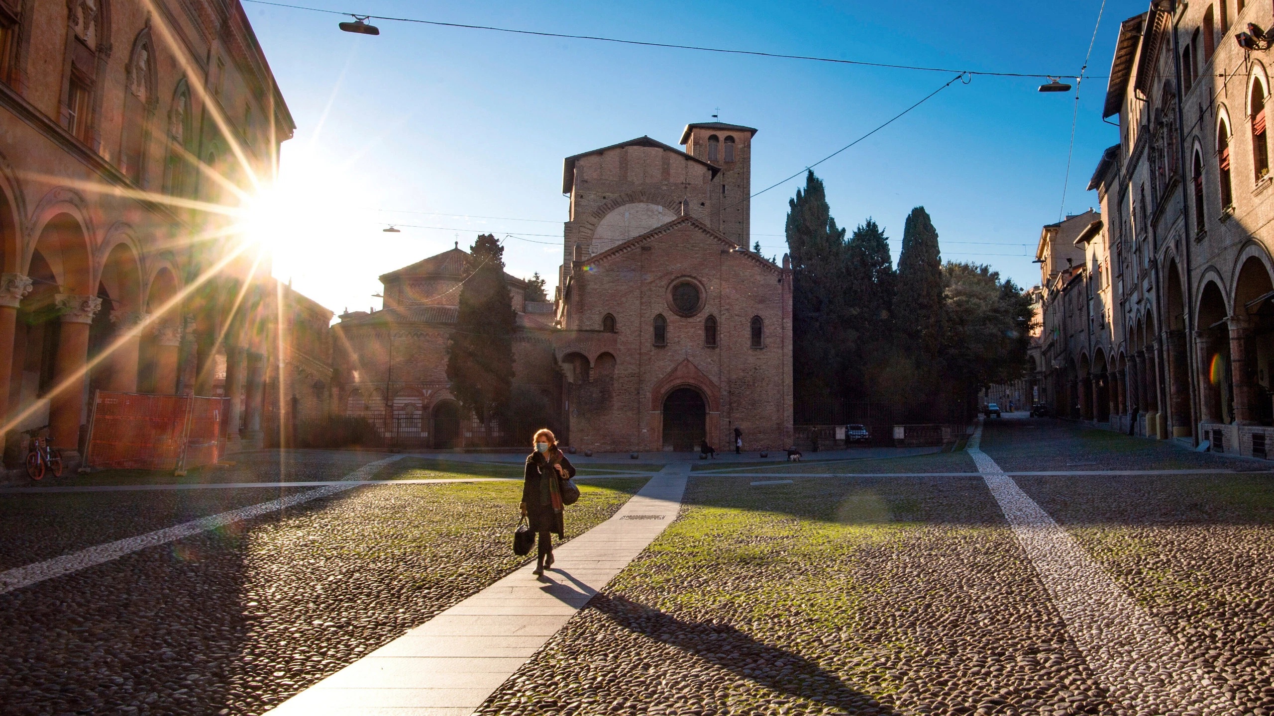 A woman walks past the Basilica of Santo Stefano in Bologna Italy