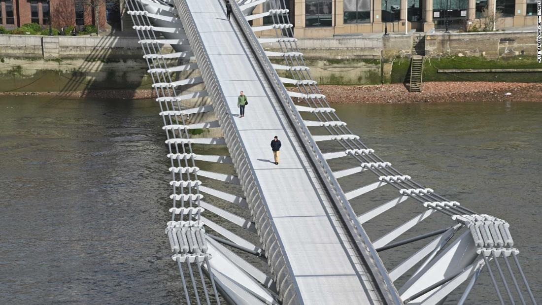 Pedestrians cross a quiet Millennium Footbridge across the River Thames in London