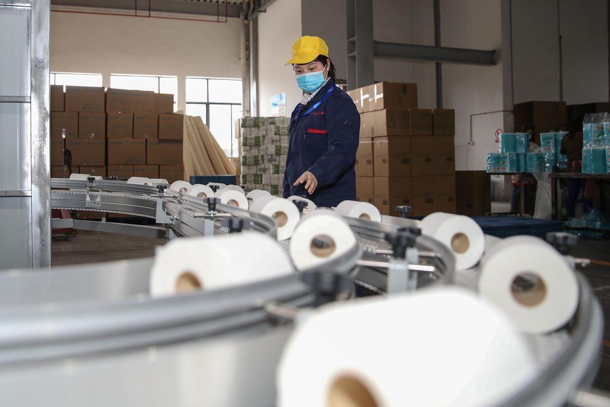 An employee produces toilet paper for exporting on the production line of a paper company
