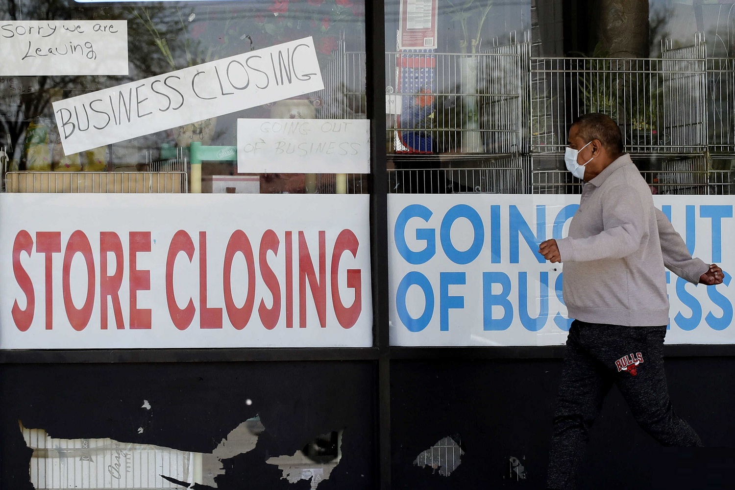 A man looks at signs of a closed store due to COVID 19