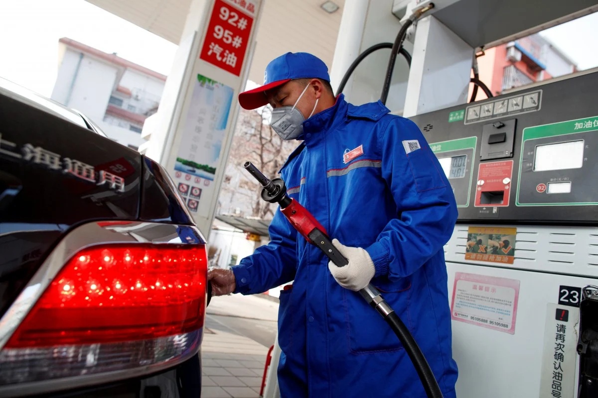 A pump attendant refuels a car at a gas station